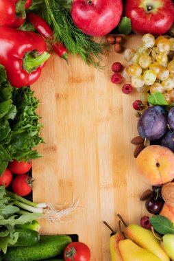Tahta bir tahtanın etrafında sebzeler ve meyveler. Sağlıklı gıda konsepti. Metin yazmak için alanı olan parlak arkaplan.