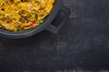 Siyah arkaplanda biberli pilav ve tavşan paella ayrıntıları.
