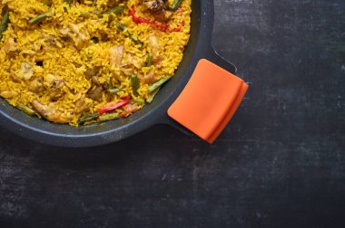 Siyah arkaplanda biberli pilav ve tavşan paella ayrıntıları.
