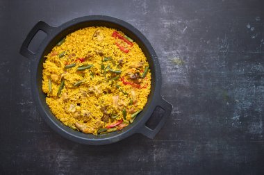 Siyah arkaplanda biberli pilav ve tavşan paella ayrıntıları.