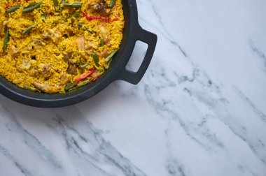 Beyaz mermer arka planda biberli pilav ve tavşan paella ayrıntıları..