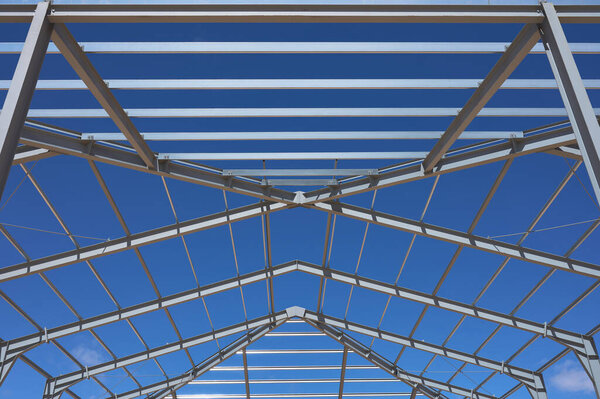 Detail of the metal structure of a building or ship in the middle of the construction with blue and cloudy sky