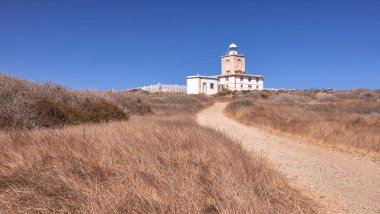 detail of a path to a lighthouse on a sunny day with blue sky