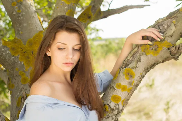 Улыбающаяся девушка возле дерева на летнем фоне — стоковое фото