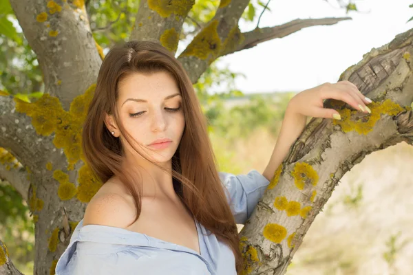 Улыбающаяся девушка возле дерева на летнем фоне — стоковое фото