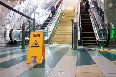 Dikkat et. Yürüyen merdivenin önündeki sarı ıslak tabela. Seçici odak