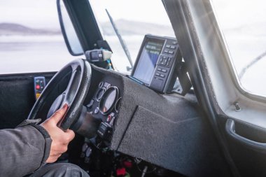 Donmuş Baykal Gölü üzerinde hareket eden bir hovercraft kullanırken direksiyon tutan sürücünün eli, seyahat yaşam tarzı konsepti.