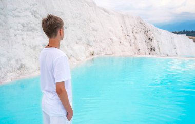 15-18 yaşlarında yakışıklı bir çocuk Pamukkale 'deki travertin havuzlarına ve teraslara bakıyor.. 