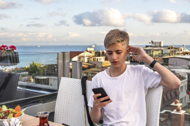 Boğazın arka planında telefon kullanan genç bir adam..