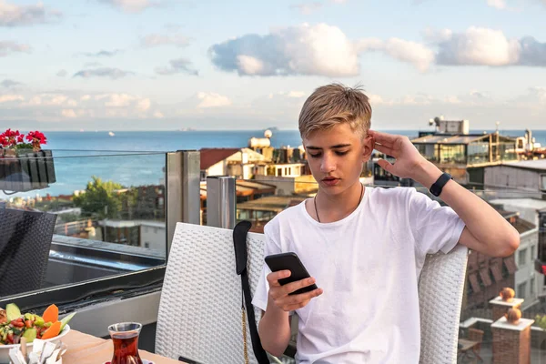 Boğazın arka planında telefon kullanan genç bir adam..