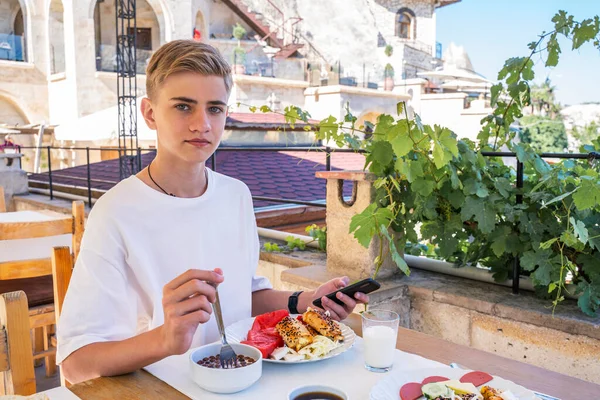 Ο έφηβος τρώει παραδοσιακό τουρκικό πρωινό σε ταράτσα με θέα την πόλη Goreme στην Καππαδοκία. Royalty Free Φωτογραφίες Αρχείου