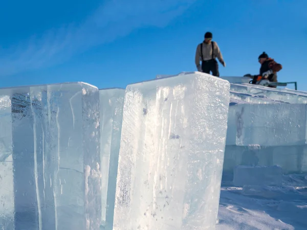 Faire des sculptures de glace. Les hommes nivelent la surface dans la glace avec une scie à essence sur le lac Baïkal. Images De Stock Libres De Droits