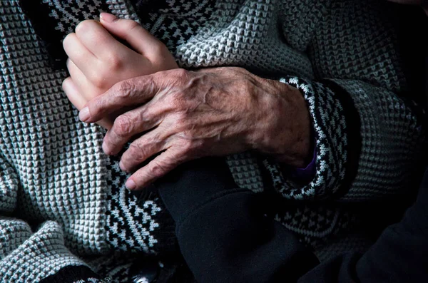 Mãos de uma mulher idosa e uma jovem sobre um fundo preto — Fotografia de Stock