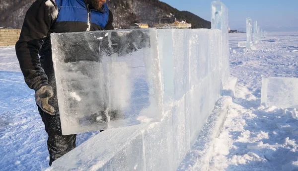 Sculpteur construit un mur à partir d'un bloc de glace sur le lac Baïkal. Photos De Stock Libres De Droits