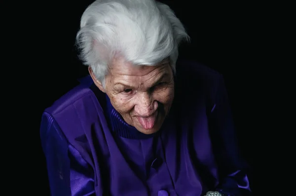 Portrait de femme âgée sérieuse sur fond noir Image En Vente