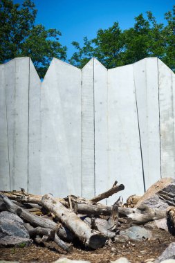 Mavi gökyüzüne ve parktaki yeşil ağaçlara karşı asimetrik duvarın dikey fotoğrafı
