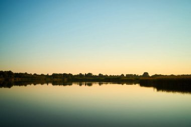 Sunset over a rural river with a blue sky in the background