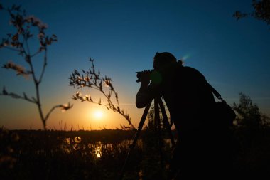 Photographer captures sunset over rural river in summer, side view 