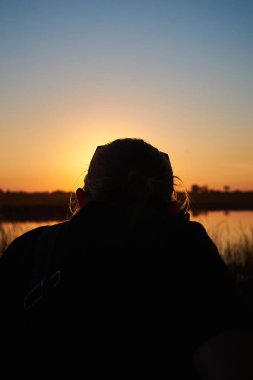 Photographer captures sunset over rural river in summer, back view