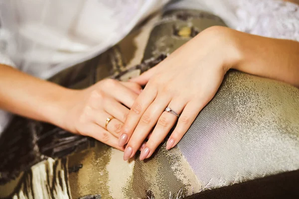 Close-up of the bride's hands with a ring lying on top of each other on the couch