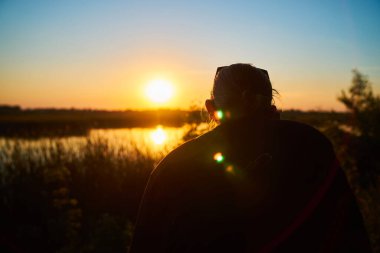 Rear view of a photographer shooting the sunset over the river