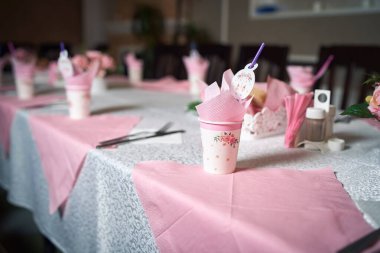 Çocuk tatilinin neşeli masasında pembe tonlarda içki bardağı içen bir karton fotoğraf.