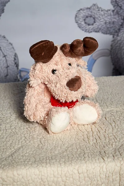 Bir çocuğun pastel renkli yumuşak oyuncak geyiğinin dikey fotoğrafı bir masada oturuyor ve başka tarafa bakıyor.