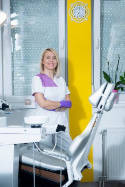 Profesyonel kadın hemşire bir diş kliniğinde duruyor.