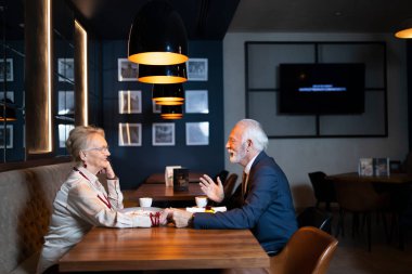 Yaşlı karı koca özel bir restoranda sohbet ediyorlar.