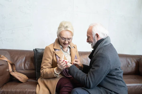 Grateful elderly woman receiving a ring by her partner during a Valentines day