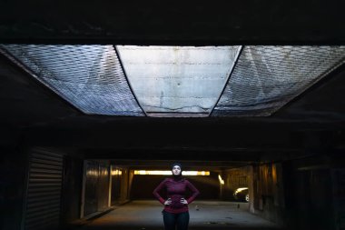 Müslüman kadın ayakta duruyor ve dramatik bir ışık altında kararlar veriyor.