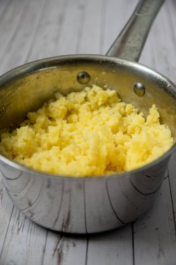 Mashed puree potatoes in silver pan on a wooden table background