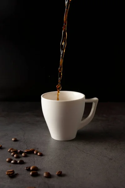 Filling a coffee cup with coffee in slow motion on a concrete background