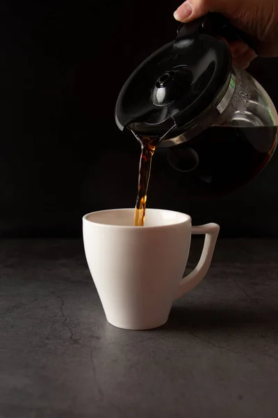 Filling a coffee cup with coffee in slow motion on a concrete background