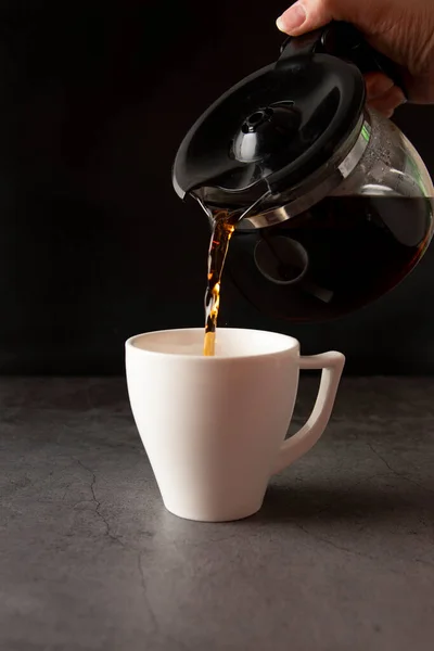 Filling a coffee cup with coffee in slow motion on a concrete background