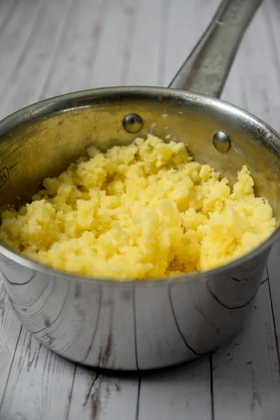 Mashed puree potatoes in silver pan on a wooden table background