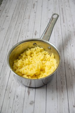 Mashed puree potatoes in silver pan on a wooden table background