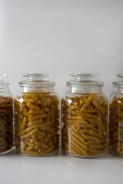 Different types of italian pasta standing next to each other in a glass jars