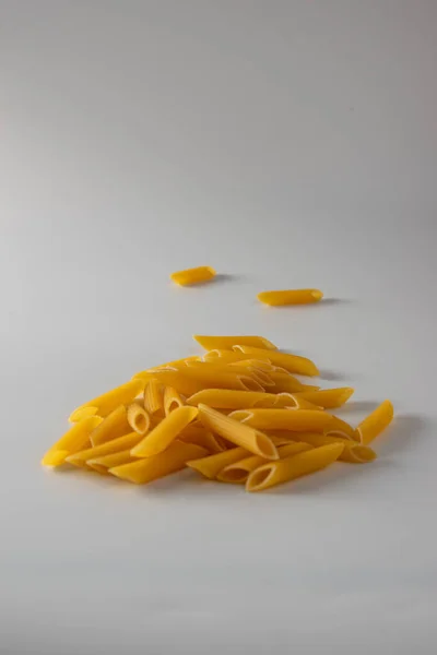 Penne rigate italian pasta scattered freely on a white background