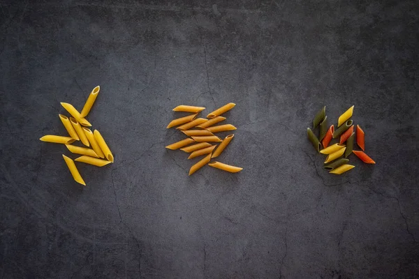 Three types of penne pasta, wholemeal, integrale, tri colore and regular on a background