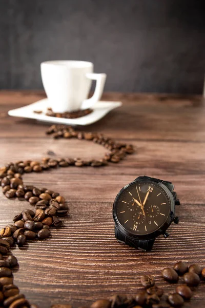 Watch showing best time for coffee with cup of coffee in the background on the wooden table