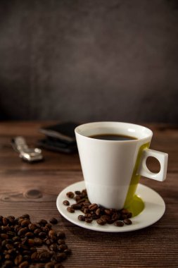 Coffee cup on a wooden table with wallet and watch