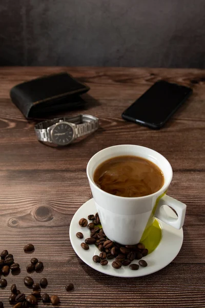 Coffee cup on a wooden table with wallet and watch