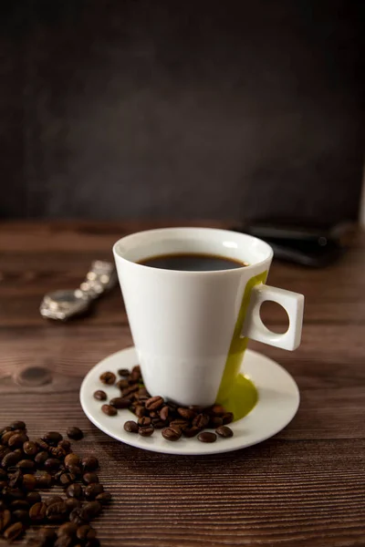 Coffee cup on a wooden table with wallet and watch