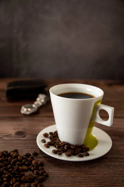 Coffee cup on a wooden table with wallet and watch