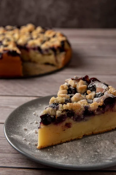 Piece of blueberry cake on wooden table with sugar powder