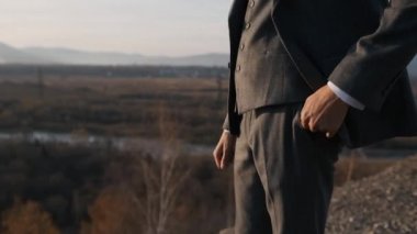 Takım elbiseli bir adam elini uçurumun kenarına koyar.