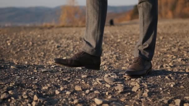 Zbliżenie nogi biznesmena w brązowych butach i garnitur spacerując pewnie po przyrodzie na tle gór — Wideo stockowe