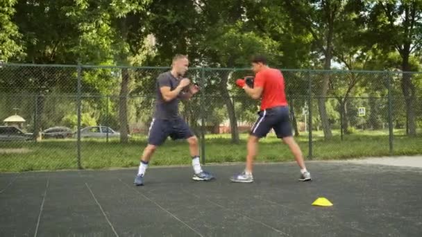 Бокс. Молодой кавказский юноша тренируется со своим тренером на улице. Спорт и здоровье — стоковое видео