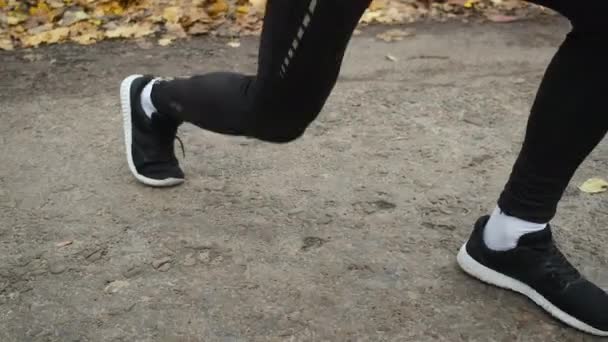 Close-up shot of an athletes legs in a park that is warming up — Stockvideo